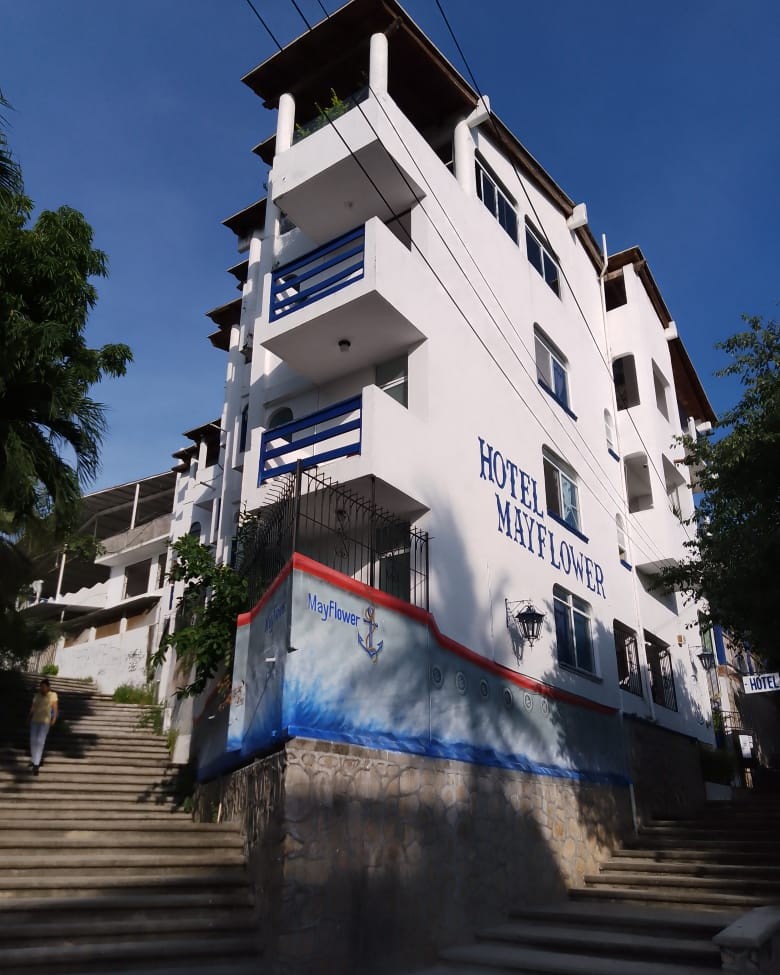 Front of MayFlower Hotel & Hostal seen from the street steps, with its painted wave mural and anchor