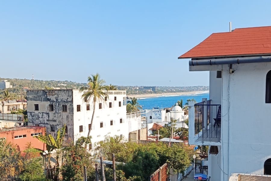 View toward the sea from MayFlower Hotel & Hostal on a clear day, with the town rooftops and the bay